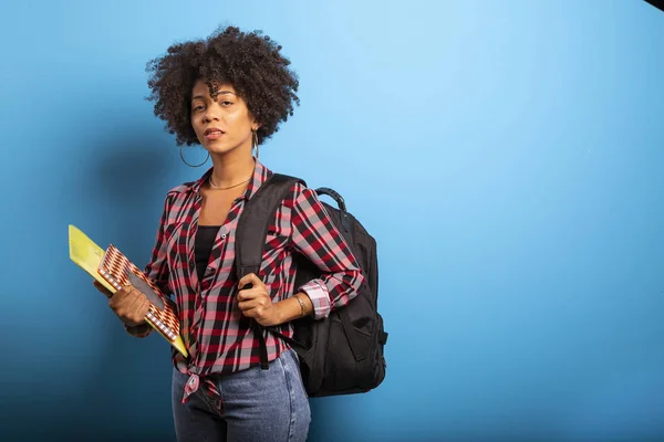 Joven estudiante africano con mochila en la espalda sobre fondo azul . — Foto de Stock