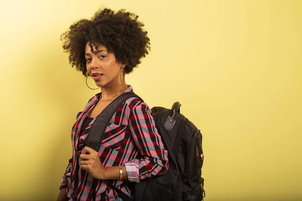 Joven estudiante africano con mochila en la espalda sobre fondo amarillo . — Foto de Stock