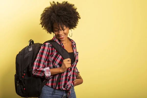 Joven estudiante africano con mochila en la espalda sobre fondo amarillo . — Foto de Stock