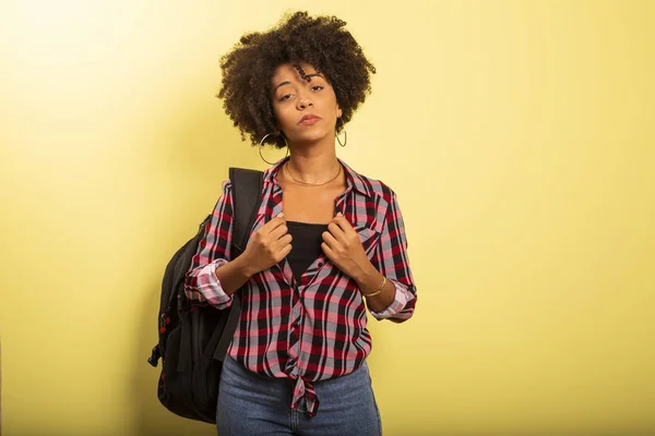 Joven estudiante africano con mochila en la espalda sobre fondo amarillo . — Foto de Stock