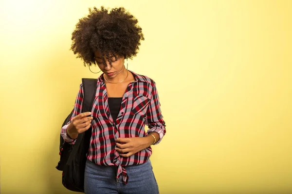 Joven estudiante africano con mochila en la espalda sobre fondo amarillo . — Foto de Stock