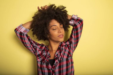 Genç Afrikalı bir kadın, sarı duvarlı stüdyoda izole edilmiş genç kız tarzı bağırıyor..