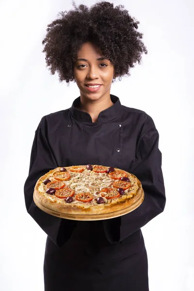 Beyaz arka plan üzerinde elinde bir pizza tutan afrikalı aşçı kadın. — Stok fotoğraf