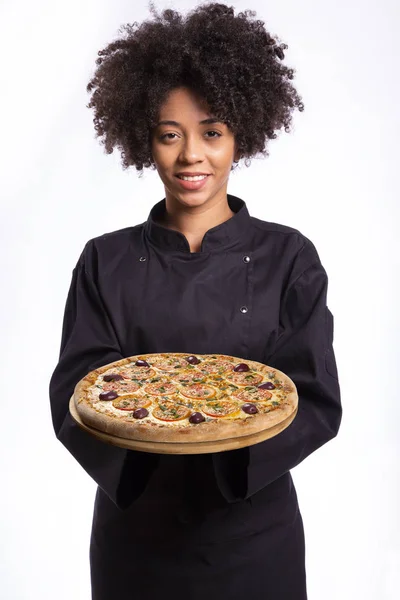 Africano cuoco donna holding un pizza in il mani su bianco sfondo . — Foto Stock