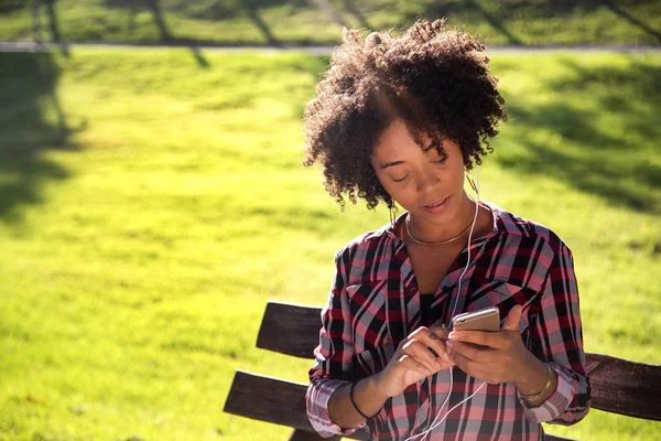 Retrato de una joven afroamericana escuchando música en un celular - Imagem . — Foto de Stock