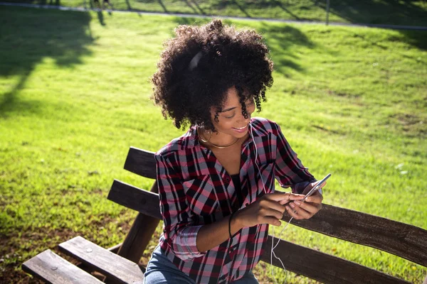Retrato de una joven afroamericana escuchando música en un celular — Foto de Stock