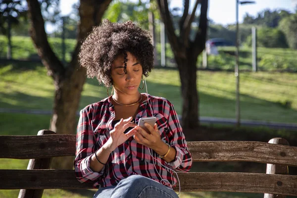 Retrato de una joven afroamericana escuchando música en un celular — Foto de Stock