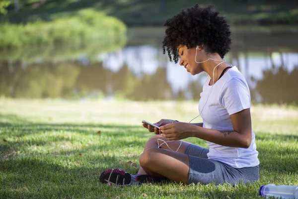 Retrato de una joven afroamericana escuchando música en un celular - Imagem . — Foto de Stock