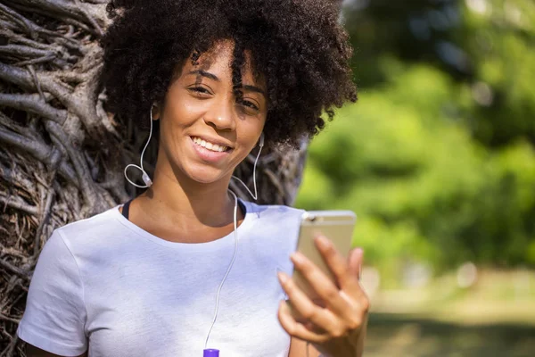 Retrato de una joven afroamericana escuchando música en un celular - Imagem . — Foto de Stock