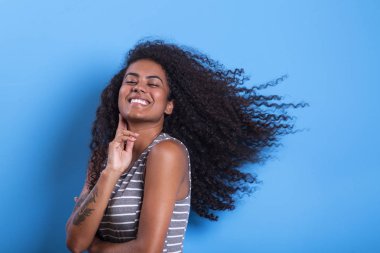 Mavi arka planda afro saç modeli ile gülümseyen siyah kadın Portresi - Imagem.