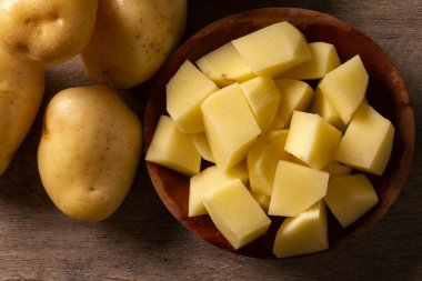 Ahşap masanın üzerine dilimlenmiş patates ve patates. Seçici odak