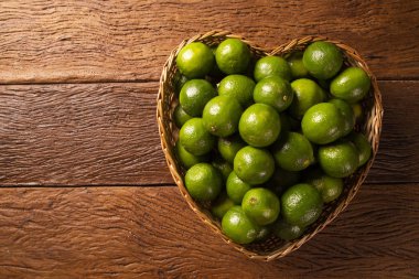 Ahşap masa arka plan üzerinde bir kalp kase taze kireç. Üstte görüntü