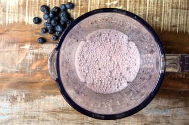 Blender üst görünümü içine yaban mersini suyu. Kırmızı meyve