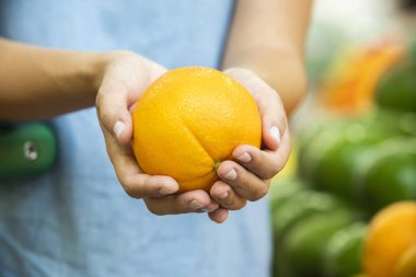 Kadının eli süpermarkette portakal meyvesi seçiyor. 