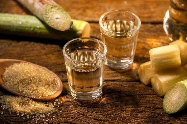 Два стакана бразильского золота качака с сахаром и сахарным тростником изолированы на деревенском деревянном фоне . — стоковое фото