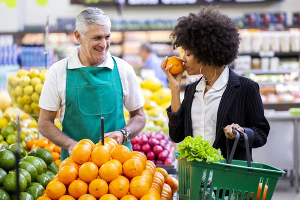 Afrikansk kund med greengrocer, som innehar apelsin frukt. — Stockfoto