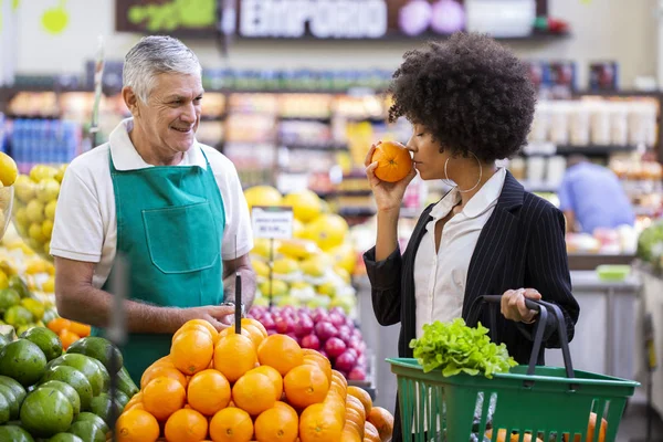 Afrikansk kund med greengrocer, som innehar apelsin frukt. — Stockfoto