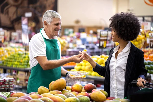 Afrikansk kund med greengrocer, Holding mango. — Stockfoto