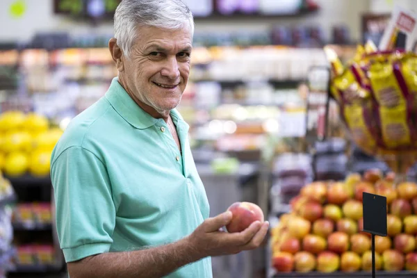 Stilig man poserar, ser och håller frukt i handen. Skäggiga kund leende. Avsnitt med färska citrus på bakgrund. — Stockfoto