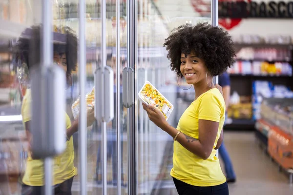 Afrikansk kvinna plocka upp produkten i stormarknaden kylskåp — Stockfoto