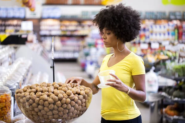 Adult kvinnlig afrikansk kund välja nötter i snabbköpet — Stockfoto