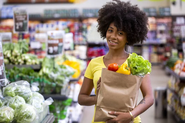 Sana donna africana felice positivo in possesso di un sacchetto di carta pieno di frutta e verdura . — Foto Stock