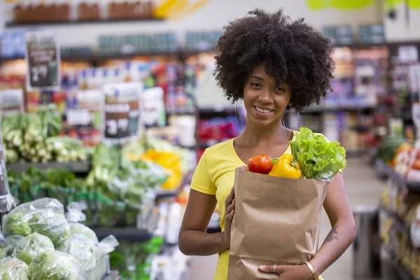 Sana donna africana felice positivo in possesso di un sacchetto di carta pieno di frutta e verdura . — Foto Stock