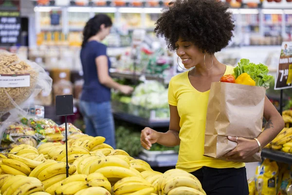 Friska positiva lycklig afrikansk kvinna som innehar en papperspåse full av frukt och grönsaker. — Stockfoto