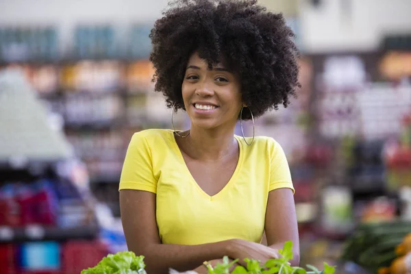 Friska positiva lycklig afrikansk kvinna som innehar en kundvagn full av frukt och grönsaker — Stockfoto