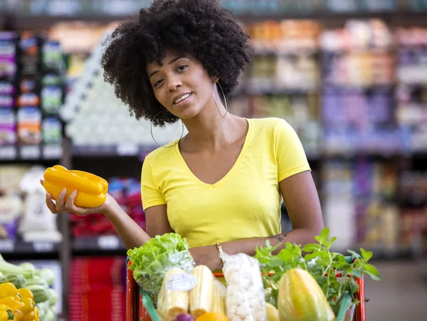 Friska positiva lycklig afrikansk kvinna som innehar en kundvagn full av frukt och grönsaker — Stockfoto