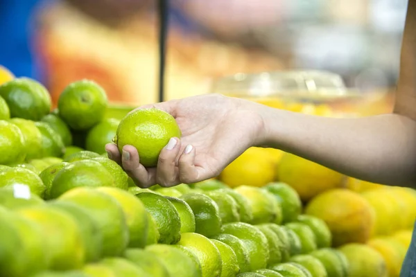 Kvinnans hand väljer citroner i snabbköpet — Stockfoto