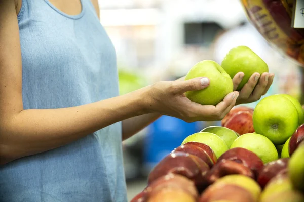 Kvinnans hand väljer grönt äpple i snabbköpet — Stockfoto