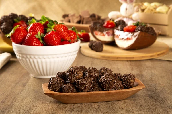 Brazilian chocolate truffle bonbon brigadeiro on wooden table with strawberry and easter background