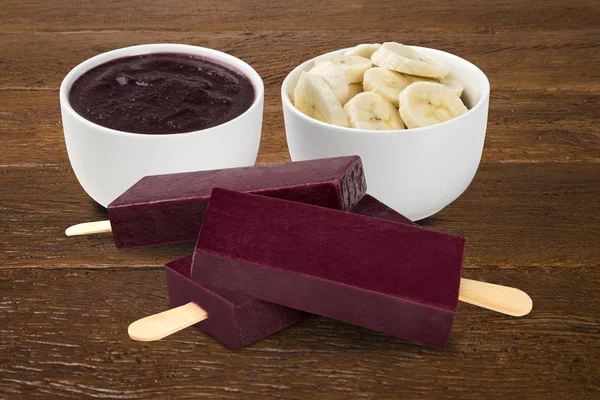 Stick ice cream acai with banana flavor isolated on wood background. Mexican Pallets.