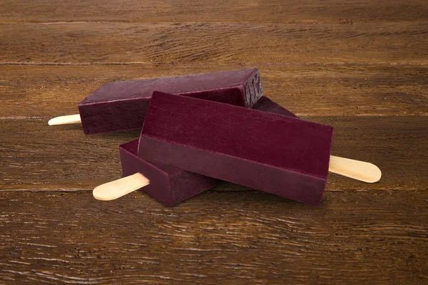 Stick ice cream acai with banana flavor isolated on wood background. Mexican Pallets.