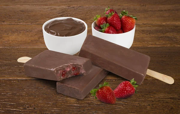 Stick ice cream chocolate with strawberry cream flavor isolated on wood background. Mexican Pallets.