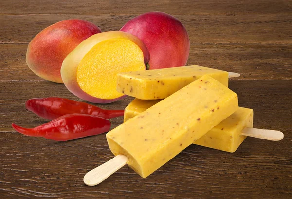 Stick ice cream mango with pepper flavor isolated on wood background. Mexican Pallets.