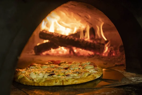 Pizza italiana en un horno de leña — Foto de Stock