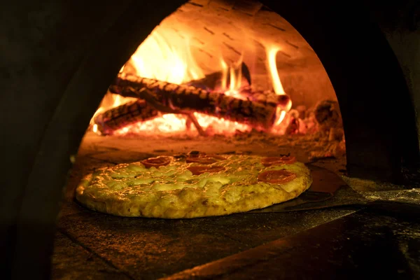 Pizza italiana en un horno de leña — Foto de Stock