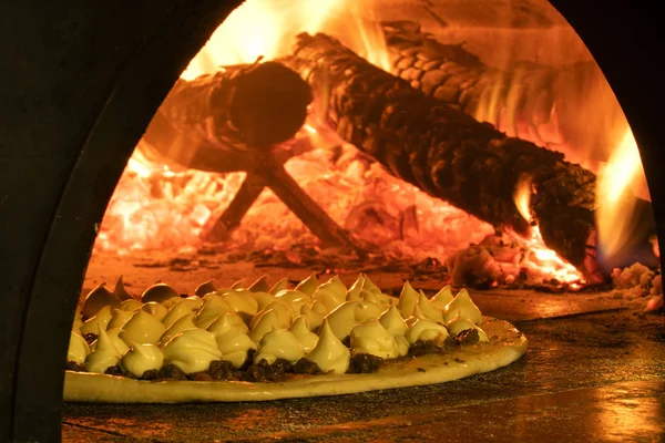 Pizza italiana en un horno de leña — Foto de Stock