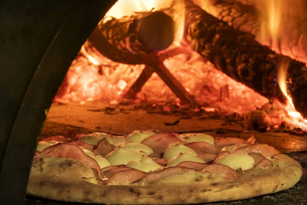 Pizza italiana en un horno de leña — Foto de Stock