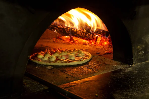 Pizza italiana en un horno de leña — Foto de Stock