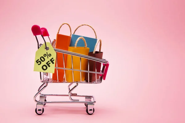 Gifts in shopping cart on rose background