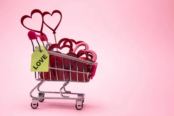 Heart in shopping cart on rose background