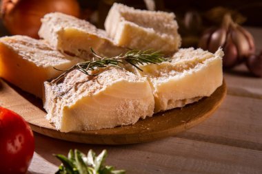 Ahşap masada malzemelerle birlikte tuzlanmış morina balığı. Morina balığı çiğ