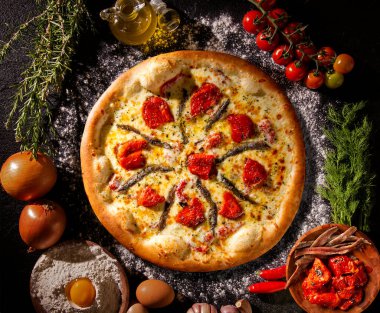 Siyah beton arka planda pizza ançüez ve kurutulmuş domates. Üst Manzara, kapat. Geleneksel Brezilya Pizzası