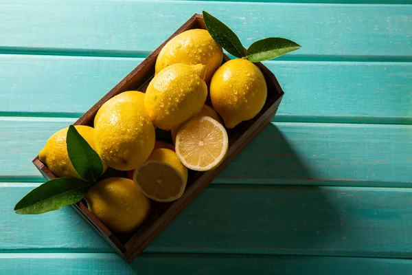 Wood box with lemons on green wooden background.