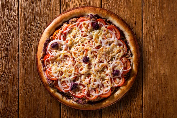 Pizza tuna fish, onion, tomato and black olive on wood background. Top view, close up. Traditional Brazilian Pizza