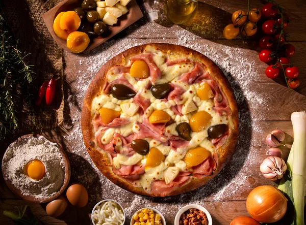 Sweet pizza with peaches, fig and pineapple on wood background. Top view, close up. Traditional Brazilian Pizza