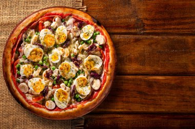 Geleneksel Portekiz pizzası, yumurta, zeytin, palmiye kalbi ve bezelye. Ahşap arka plan manzaralı, yakın çekim. Geleneksel Brezilya Pizzası.